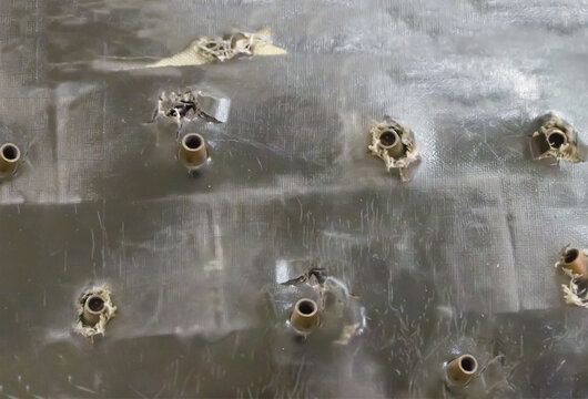 old bulletproof vest riddled with large-caliber weapons with stuck shells close-up