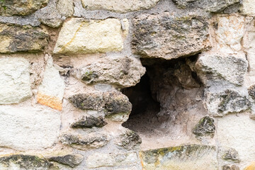 gray stone wall of the fort with a hole close-up, a wall of large blocks