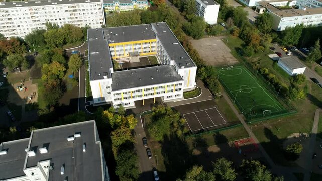 School building surrounded by residential neighborhoods. Stadium provides place for sports events. Meticulously planned educational complex