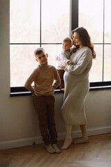 Young mother-to-be with her elder sons are relaxing and playing in the studio together,  warm and...