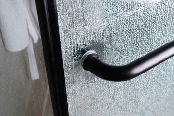 Limescale on transparent glass of shower cabin close-up, plumbing maintenance concept
