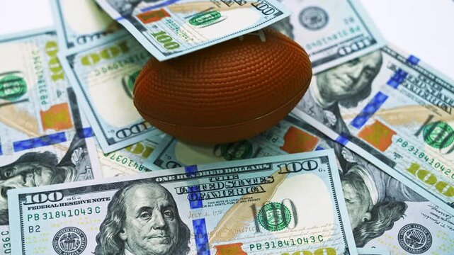 Rugby ball on stack of dollars spinning on table  