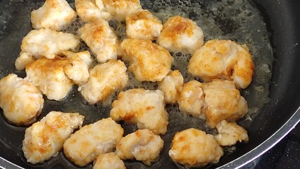 Chicken breast pieces are fried in a frying pan