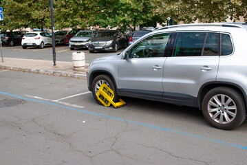 Nessebar, Bulgaria - September 2, 2024: A front car wheel blocked by wheel lock for unauthorized or illegal parking. Wheel lock on wheel of vehicle on street