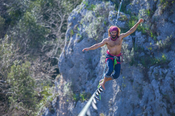 A tightrope walker walks along a cable stretched over a canyon.