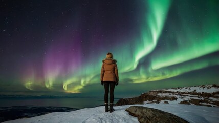 Fototapeta premium Woman on cliff watching northern lights