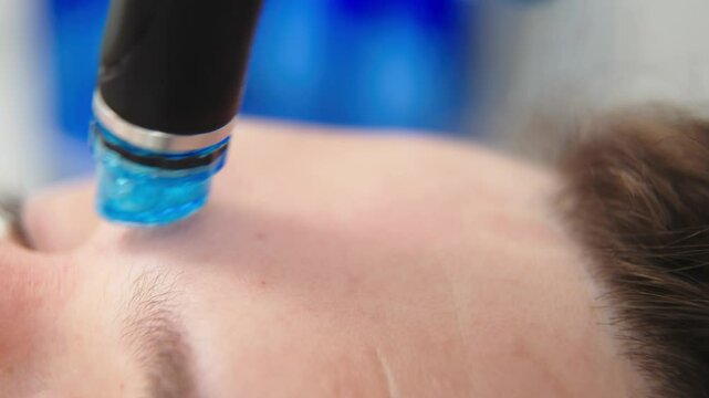 Facial skin care. A professional female cosmetologist performs a hydraulic procedure on a man in a cosmetology clinic. Vacuum cleaner Hydra. Rejuvenation and hydration