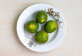 Fresh green malta fruits on a white plate on a wooden background. Top view.