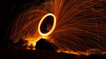 Swing fire Swirl steel wool light photography over the stone with reflex in the water Beautiful...