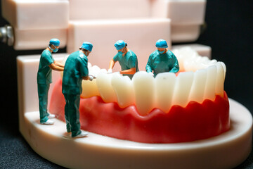 Miniature figurines of surgeons working on a large model of human teeth