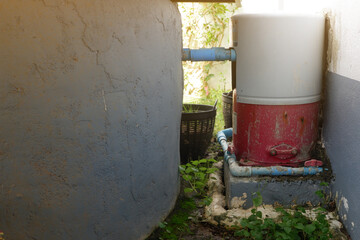 High pressure automatic water pump installed between the house wall and the well to suck water from the well for use inside the house.