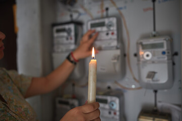 Checking the electricity power meter with a candle in cold winter days while there is power outage.