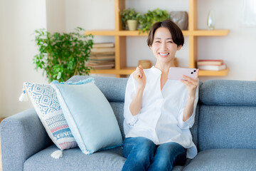 部屋でスマホを操作するミドル女性