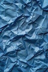 Obraz premium Crumpled blue fabric texture with shiny material. Close-up view of folded and creased surface. Prominent blue color stands out in this high-angle shot.