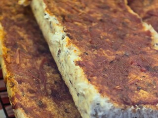 Close-up of a traditional baked tofu dish with a savory, textured topping. The crispy edges and layers showcase the flavors and textures, perfect for vegetarian meals.

