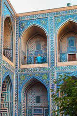 Obraz premium Woman in blue traditional clothing in the courtyard of the Ulugbek Madrassah.