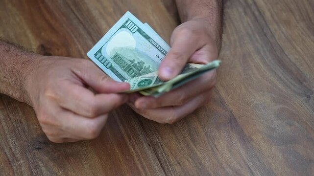 Entrepreneur counts dollar banknotes in warehouse tallying earnings from recent online sales and strategizing on reinvesting profits in expanding product line