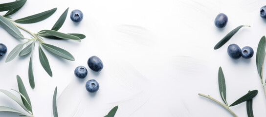 Fototapeta premium Black olives scattered with olive branches on a pristine white background, artistic and fresh.