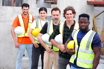 Male and female engineers wearing safety helmets standing and smiling at a construction site.