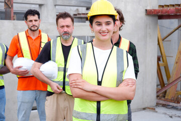 Team of engineers wearing safety helmets standing smiling at construction site.
