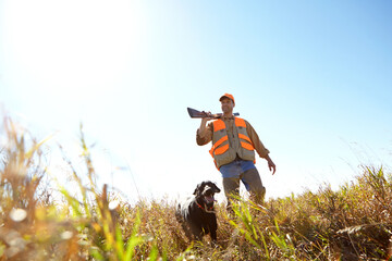 Man, dog and outdoor for hunting trip, rifle and stalking prey together in nature bush. Mature...