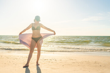 Woman standing with towel on the beach with ocean on background