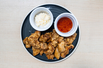 A plate of fried chicken with sauces on the side.
