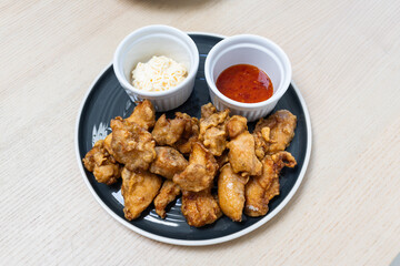 A plate of fried chicken with sauces on the side.