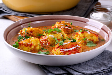 Malai Kofta served with yogurt and fresh herbs. Hot meal with potato and paneer cheese balls in tomato sauce. Indian cuisine