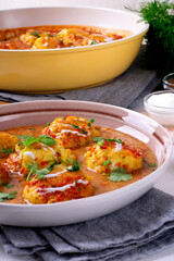 Malai Kofta served with yogurt and fresh herbs. Hot meal with potato and paneer cheese balls in tomato sauce. Indian cuisine