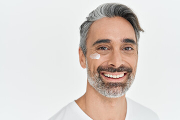 Antiage men skincare concept. Happy middle aged older man, smiling mature male model advertising facial anti age skin care cream on face looking at camera isolated on white background. Portrait.