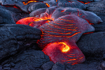Lava field in Hawaii at night shows oozing lava from the Kilauea eruption forming new rocky surfaces.