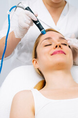 Fototapeta premium Relaxing beauty treatment in a modern cosmetic clinic. Woman enjoying a hydrolifting procedure, achieving radiant and youthful skin. Perfect for showcasing advanced skincare solutions.