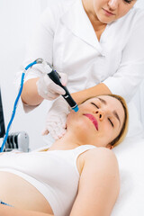 Naklejka premium Relaxing beauty treatment in a modern cosmetic clinic. Woman enjoying a hydrolifting procedure, achieving radiant and youthful skin. Perfect for showcasing advanced skincare solutions.