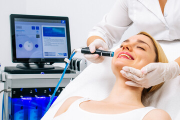 A woman receives a hydrofascial facial treatment in a modern clinic, focusing on advanced skin rejuvenation techniques and contemporary skincare practices.