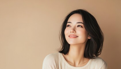 portrait of softly smiling beautiful brunette woman is 35 years old on solid light beige color background with copy space