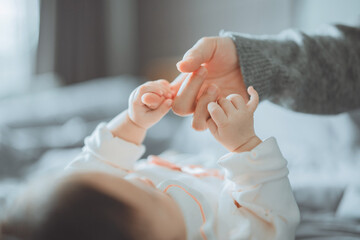 Close-up little hand of child baby holding hand of mother, A newborn holds on to mom's, dad's finger, Love and relationship with infant, Care and support, Dreaming and protection