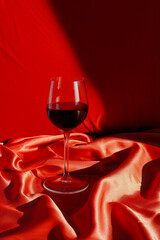 A wine glass is sitting on a red cloth