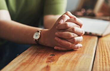 Woman, hands and praying on desk for worship, jesus christ and christian praise for salvation in home. Female person, spiritual healing and thank you to God, practice religion and grace for peace