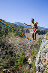 A tightrope walker walks along a cable stretched over a canyon.