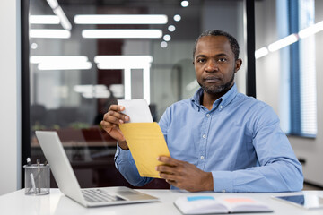 Office worker organizing documents while using laptop. Concept of efficiency, focus, and productivity in modern workspace. Worker demonstrates precision in handling paperwork.