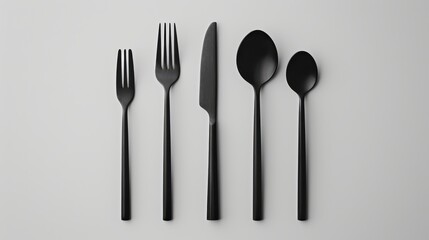 Set of modern matte black cutlery with two forks, knife and two spoons symmetrically arranged on light background. Concept of minimal table aesthetics