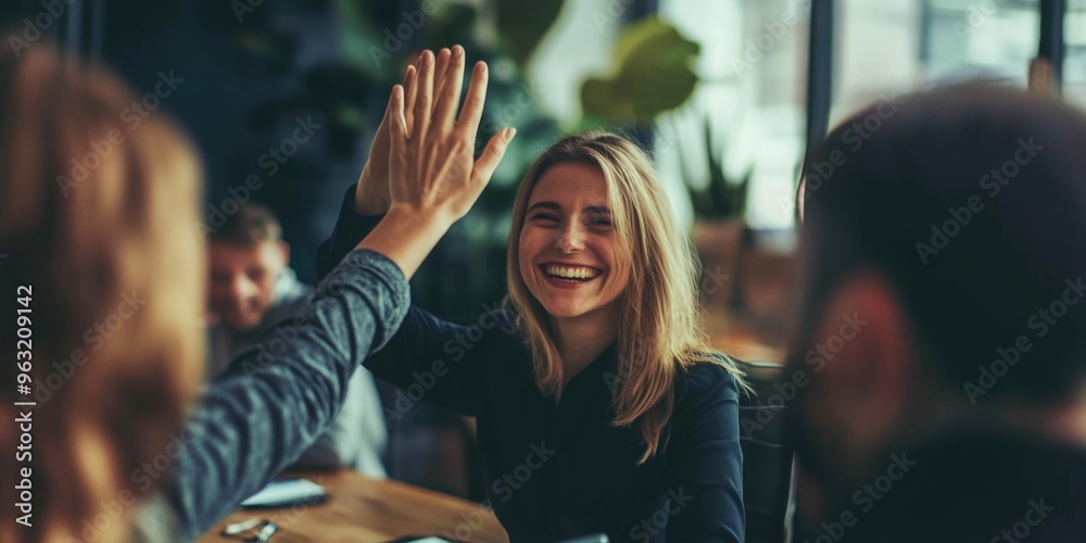 Canvas Prints a woman is smiling and giving a high five to another woman. the scene is set in a room with a table 