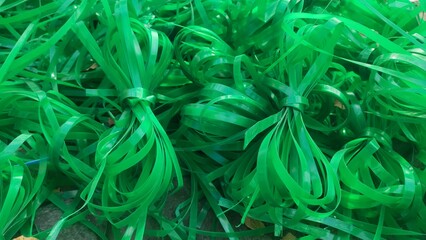 An abstract close-up of green plastic strips scattered in a random pattern, showcasing their texture and vibrant color, typically used for packaging or binding purposes
