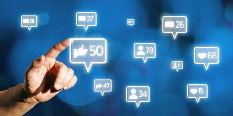 Hand interacting with glowing social media icons on blue background.