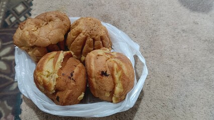 Four golden brown pastries in a plastic bag on a beige carpet.