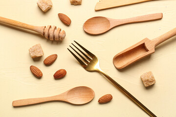 Different kitchen utensils, almond and sugar on yellow background