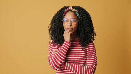 Young woman expressions thinking and wondering what to do, standing on yellow background in the studio