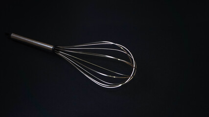 Stainless steel whisk on black background

