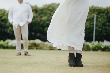 Fototapeta premium the feet of a man and a woman standing far apart on the grass